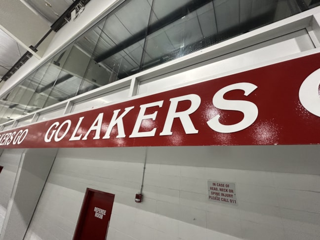 White flat cut PVC letters spelling Go Lakers Go installed around Chestermere Arena, creating a spirited and energetic atmosphere.