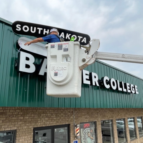 Randy installing custom signage at the South Dakota Barber College