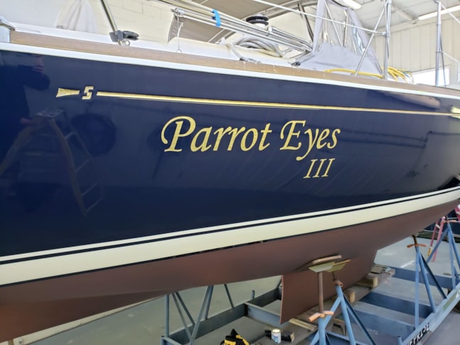 Sailboat lettering in florentine gold leaf on Flag Blue hull for Larsen Marine,  Waukegan, IL