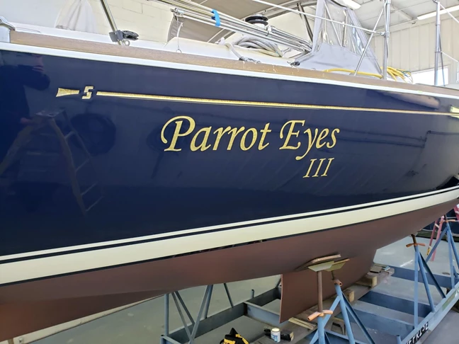 Sailboat lettering in florentine gold leaf on Flag Blue hull for Larsen Marine,  Waukegan, IL